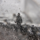 Waves and water crash around a man in the middle of a storm in Oregon.